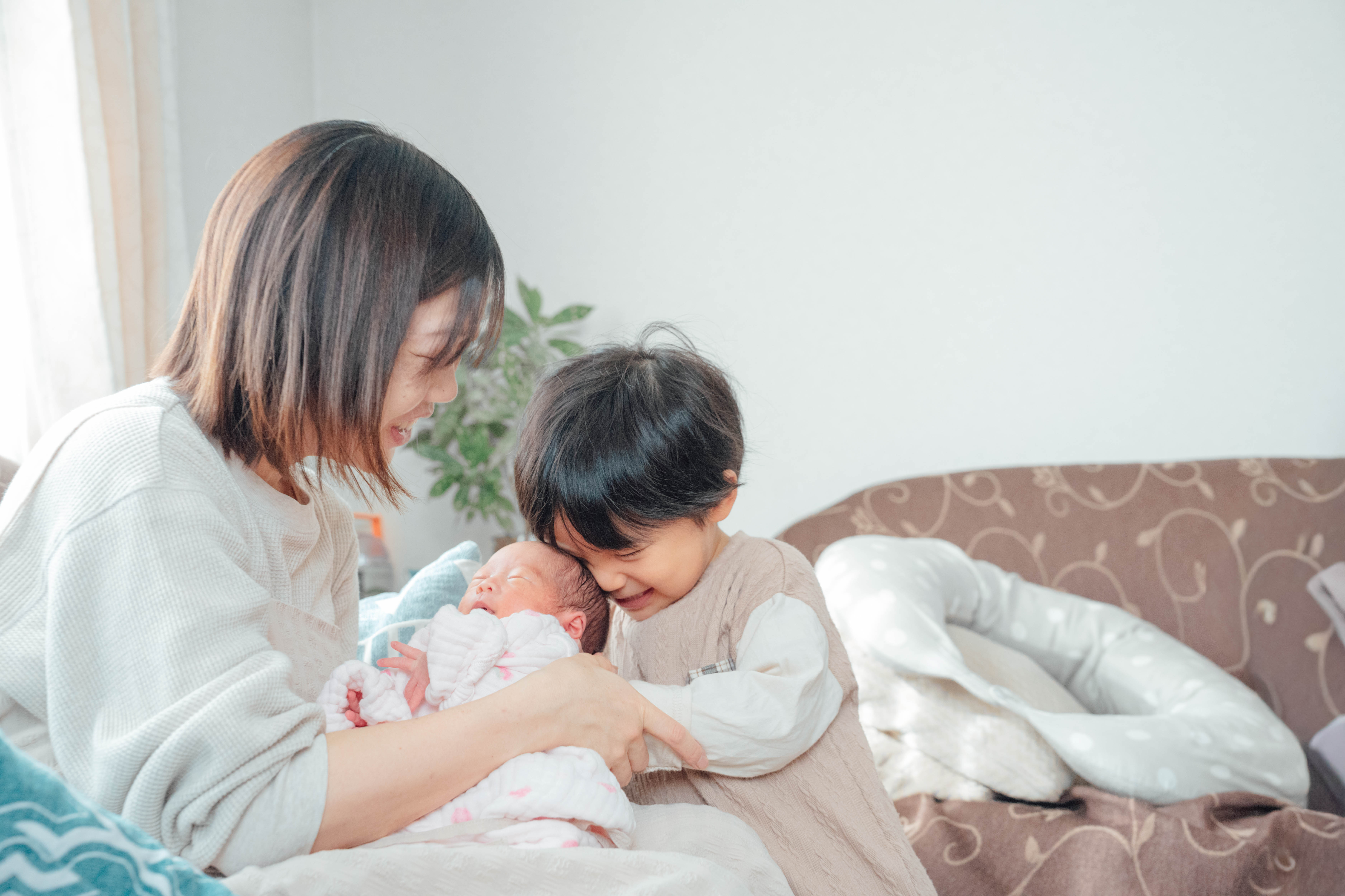 生まれたばかりの赤ちゃんをお兄ちゃんと一緒に抱くママ